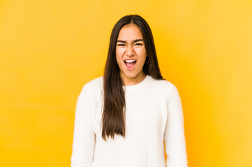 Fototapeta premium Young woman isolated on a yellow background screaming very angry and aggressive.