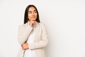 Young woman isolated on a white background looking sideways with doubtful and skeptical expression.