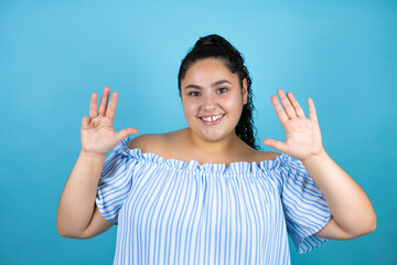 Young beautiful woman with curly hair over isolated blue background showing and pointing up with...