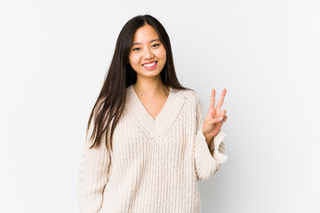 Young chinese woman isolated showing victory sign and smiling broadly.