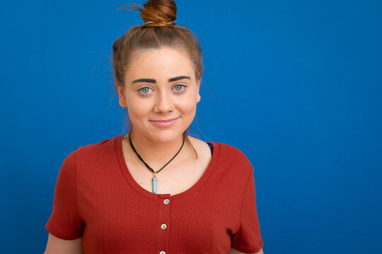 young woman with bun looking at camera against blue background