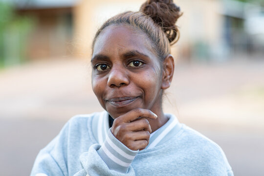 head and shoulders of young aboriginal woman looking at camera with hand to chin