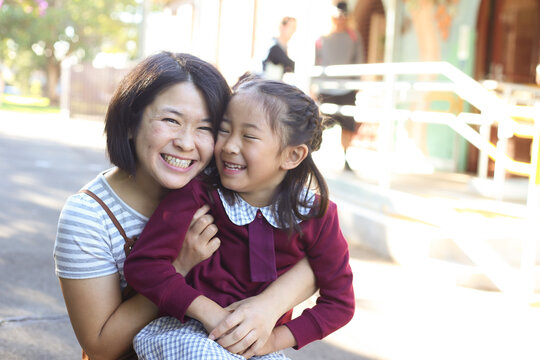 School girl sitting on her mother's knee, smiling and laughing