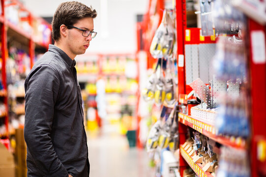Young man in hardware store looking at tools
