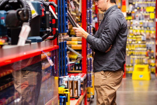 Young man in hardware store looking at tools