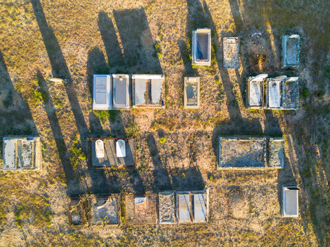 Looking down on graves in a cemetery casting shadows on the ground