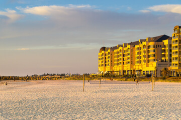 A multistory resort beside a white sandy beach with a volleyball court