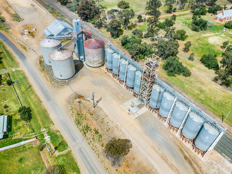 Aerial view of a row of grain silos between a road and railway line