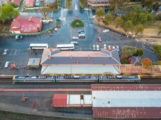 Aerial view of a train and buses at a country railway station