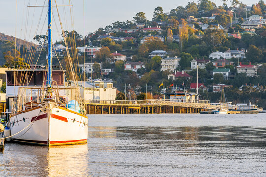 A large yacht docked at a jetty on a calm river in late afternoon sunshine