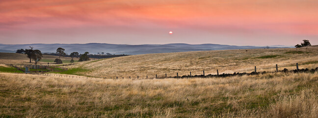 the Sun setting into a smoke filled sky over dry farmland