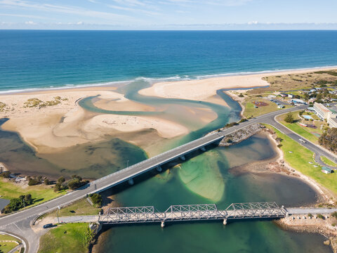 Aerial view of a river flowing under two bridges and out to sea.
