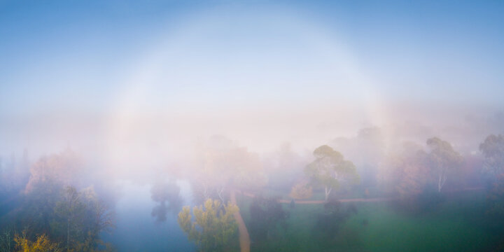 An aerial view of a fog bow hovering over a town park.