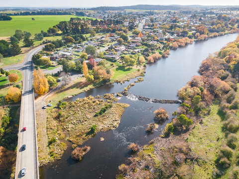 Aerial view of traffic crossing a bridge leading into a riverside country town