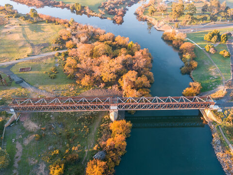 Aerial view of railway bridge spanning a river lined with Autumn trees