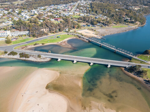 Aerial view of a river flowing through a coastal town and under two bridges