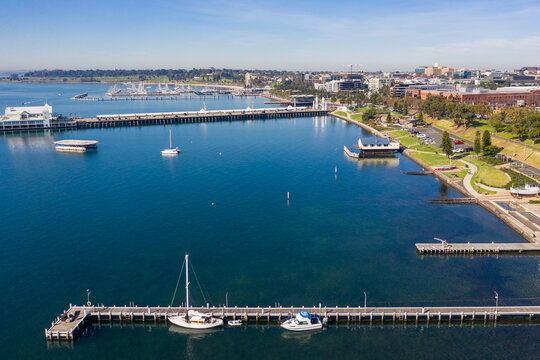 Aerial view along a city coastline with yachts and boats anchored at a jetty