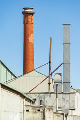 A tall brick chimney beside a large tin factory