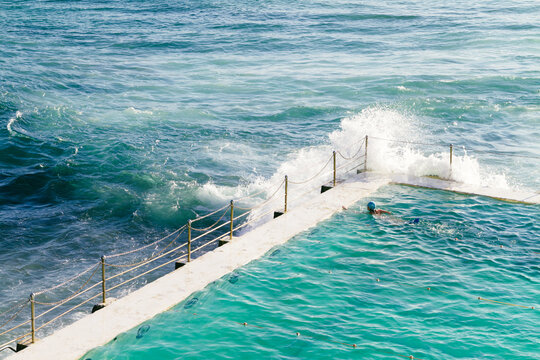 Waves crashing over the edge of Bondi Baths
