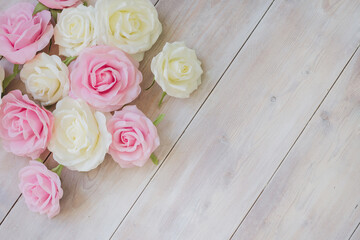 Pink and white rose buds on a white wooden background with copy space.