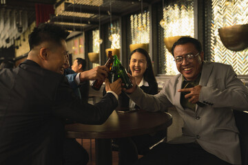 businesspeople toasting and clinking bottle of beer together