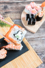Hand holding sushi roll with chopsticks