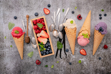 Various of ice cream flavor in cones with berries in wooden box setup on concrete background . Summer and Sweet menu concept.