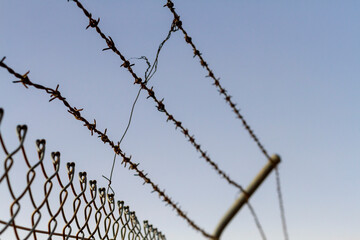 a barbed wire fence against a blue sky