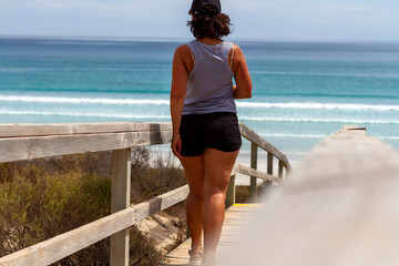 A woman on the walkway walks toward a beach on the Eyre Peninsular, South Australia