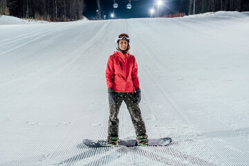 Woman with snowboard on the ski slope. Evening riding