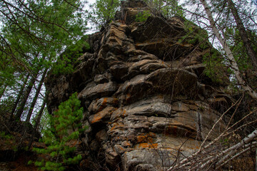 
Stone mountains. 
Stone texture. Mountain gorge. Among the huge rocky mountains there is a mountain river, the mountains are covered with fresh bright green foliage of trees in early spring.
