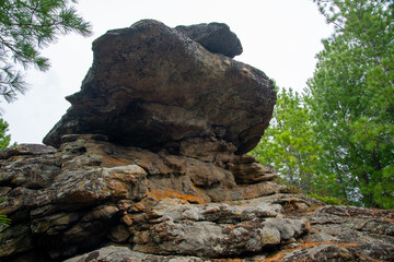 
Stone mountains. 
Stone texture. Mountain gorge. Among the huge rocky mountains there is a mountain river, the mountains are covered with fresh bright green foliage of trees in early spring.
