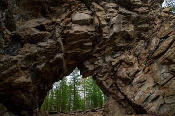 
Stone mountains. 
Stone texture. Mountain gorge. Among the huge rocky mountains there is a mountain river, the mountains are covered with fresh bright green foliage of trees in early spring.
