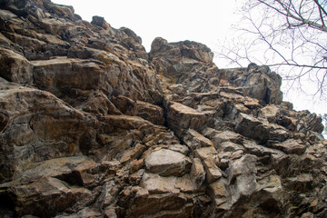 
Stone mountains. 
Stone texture. Mountain gorge. Among the huge rocky mountains there is a mountain river, the mountains are covered with fresh bright green foliage of trees in early spring.
