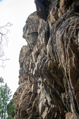 
Stone mountains. 
Stone texture. Mountain gorge. Among the huge rocky mountains there is a mountain river, the mountains are covered with fresh bright green foliage of trees in early spring.
