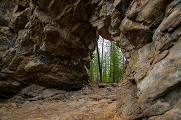 
Stone mountains. 
Stone texture. Mountain gorge. Among the huge rocky mountains there is a mountain river, the mountains are covered with fresh bright green foliage of trees in early spring.
