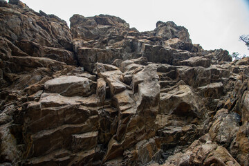 
Stone mountains. 
Stone texture. Mountain gorge. Among the huge rocky mountains there is a mountain river, the mountains are covered with fresh bright green foliage of trees in early spring.
