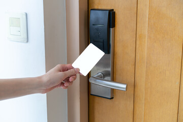 Door access control - woman hand holding white mockup key card to lock and unlock door. digital...