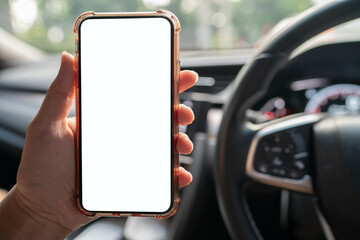 Image of hand holding mobile phone with mockup white screen in car.