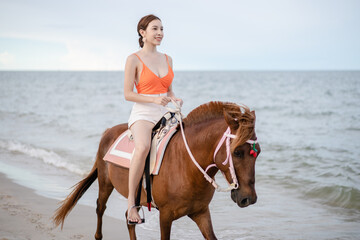 Woman riding a horse on the beach in the morning.
