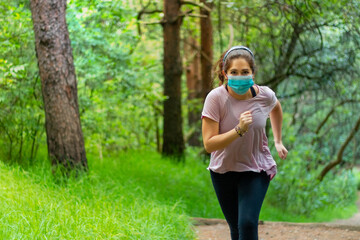 Real woman running in a forest, wearing face mask to avoid contagion of coronavirus