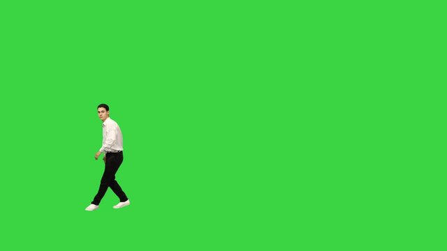 Young man in white shirt doing back flip looking at camera and walking away on a Green Screen, Chroma Key.