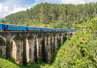 Fototapeta na wymiar Blue train on the famous Nine Arch Bridge in the jungle on the island of Sri Lanka