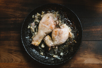 Chicken legs, onion, garlic, ,pan on cutting board top view