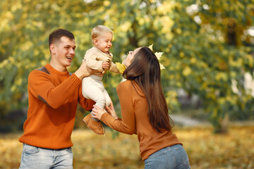 Family in a autumn park. Woman in a brown sweater. Cute little girl with parents.
