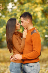 Fototapeta premium Cute couple in a park. Family in autumn clothes. Man in a brown sweater.