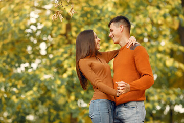 Cute couple in a park. Family in autumn clothes. Man in a brown sweater.