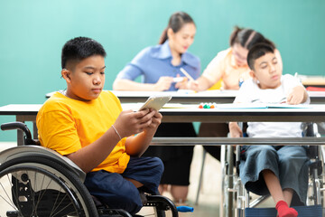asian disabled children(lost legs) using tablet and sitting on a wheelchair in classroom