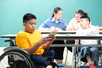 asian disabled children(lost legs) using tablet and sitting on a wheelchair in classroom