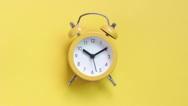 Yellow alarm clock on a yellow background close-up, top view